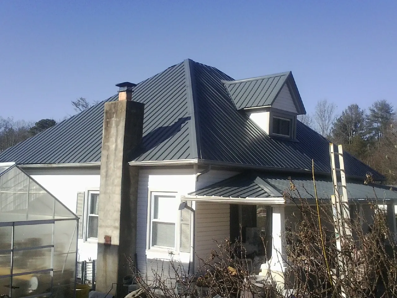 Dark blue standing seam metal roof on a white farmhouse with dormer — Slate & Tile Roof Repair by Roofing Brothers in Whitman