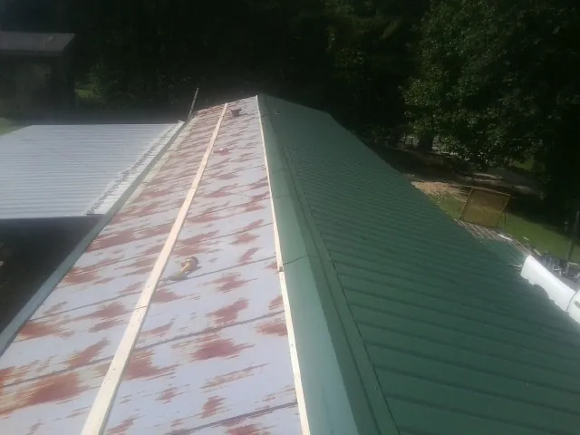 Old rusted panels beside newly installed green metal roofing — Wind Damage Roof Repair by Roofing Brothers in Whitman