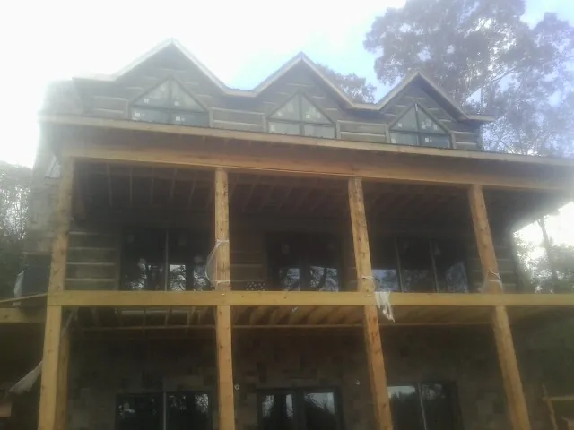 Dormers and porch framing on a large log home under construction — Roof Coating work by our crew in Whitman