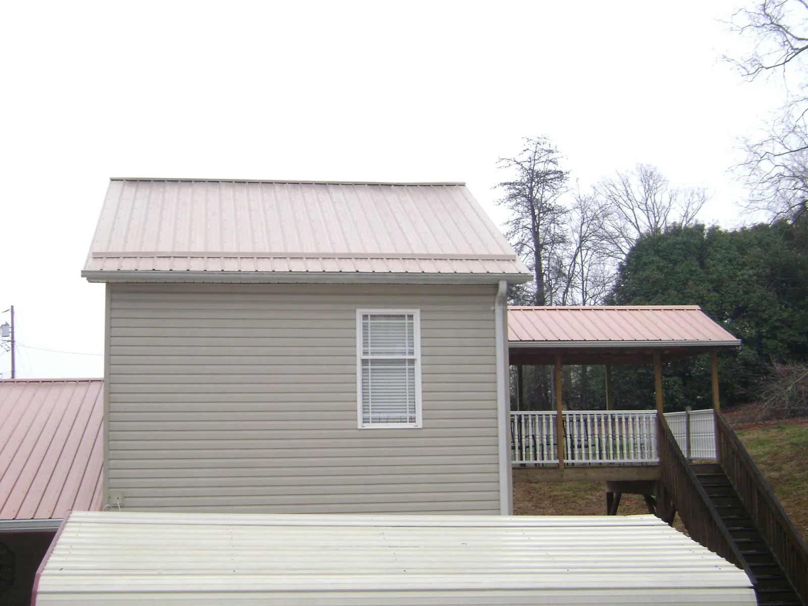 Tan metal roofs on a two story addition and attached porch, from a Roof Replacement job in Whitman