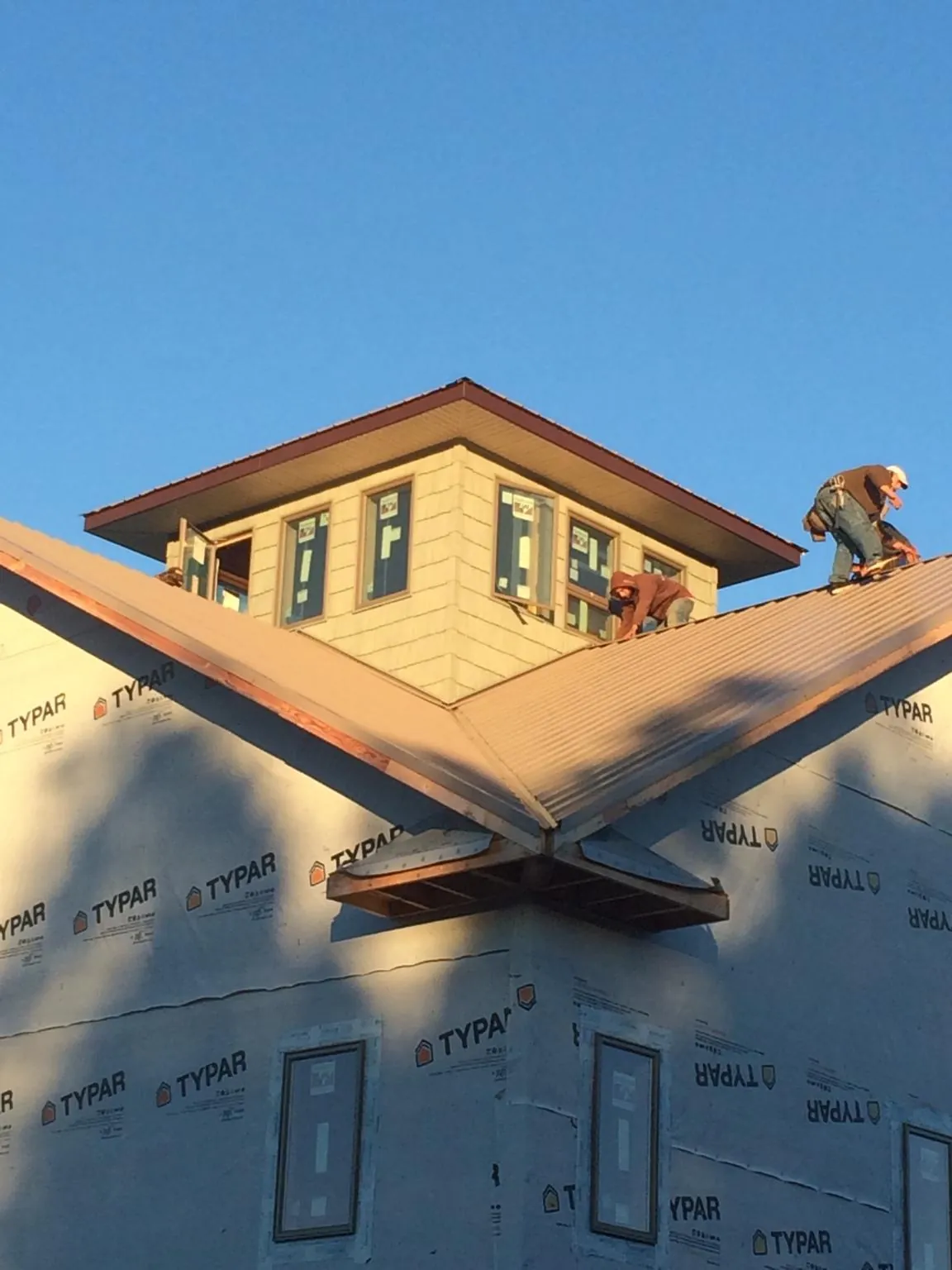 Roofers working around a rooftop cupola on a new metal roof at sunset — Roof Waterproofing in Whitman by Roofing Brothers